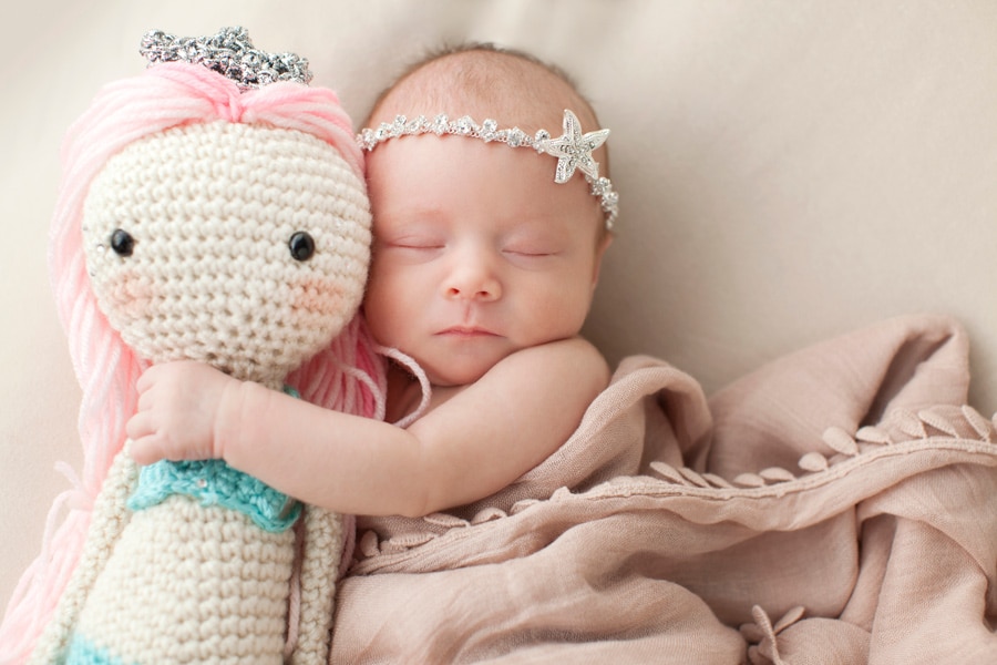 cutest newborn baby girl posing snuggled up with mermaid in Dallas Studio