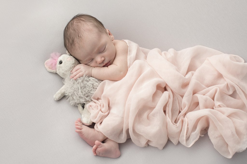 sleepy newborn girl snuggled up in studio