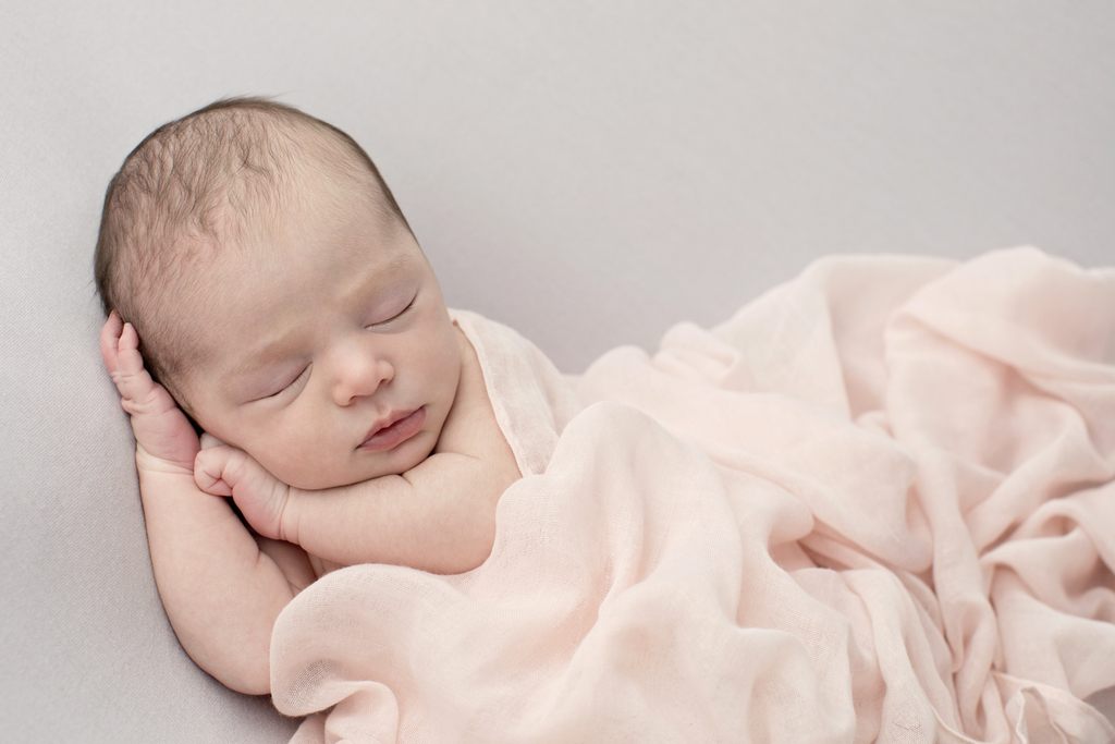 sleepy newborn girl snuggled up in studio