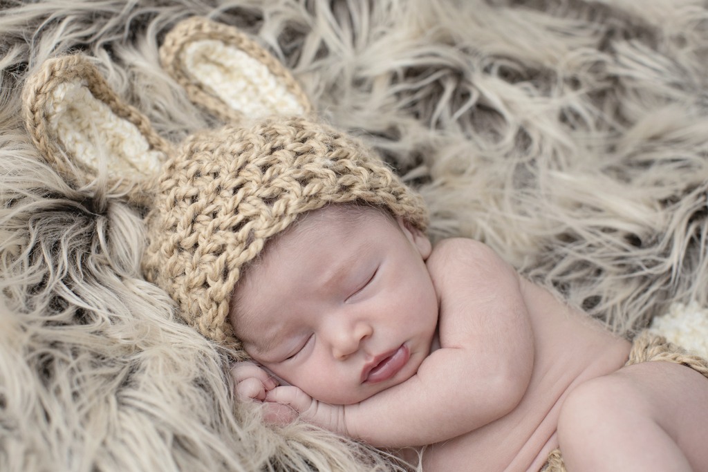 sleepy newborn girl snuggled up in studio