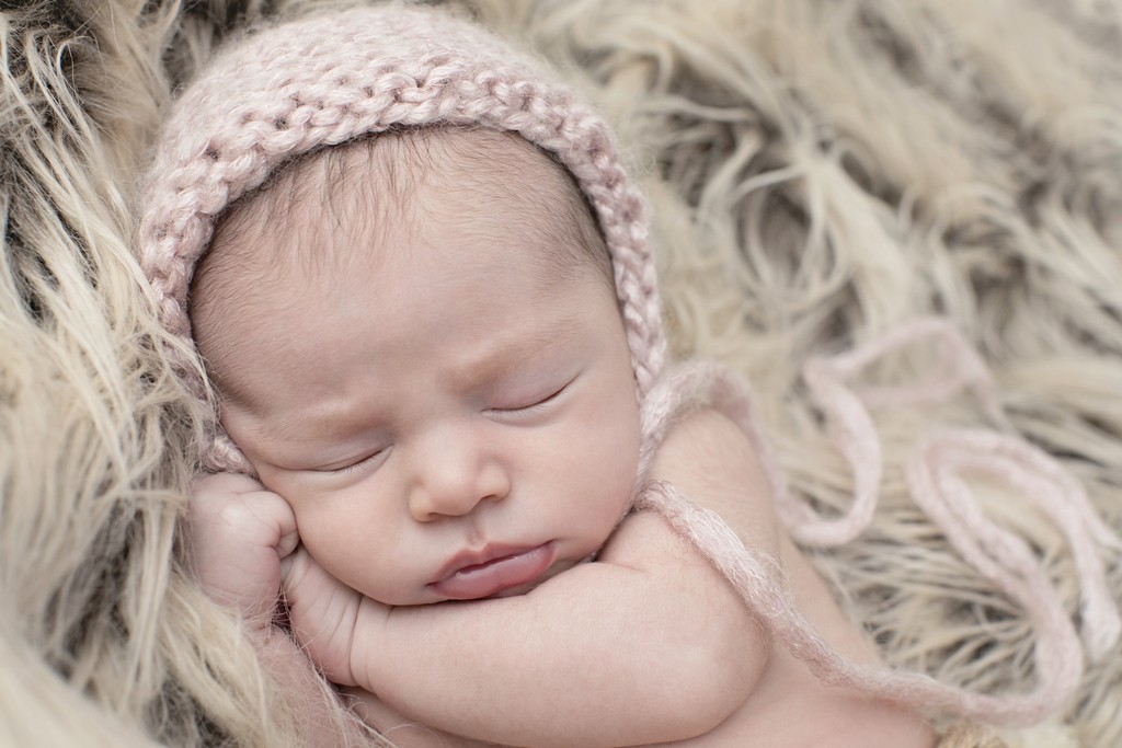 sleepy newborn girl snuggled up in studio