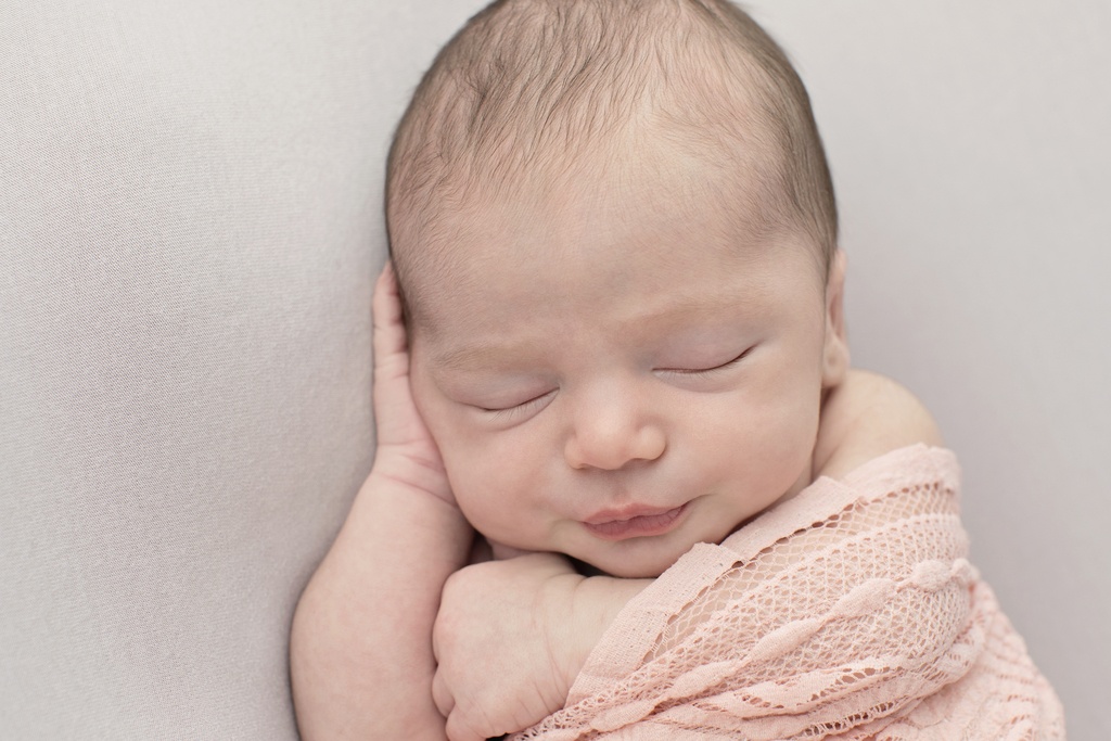 sleepy newborn girl snuggled up in studio