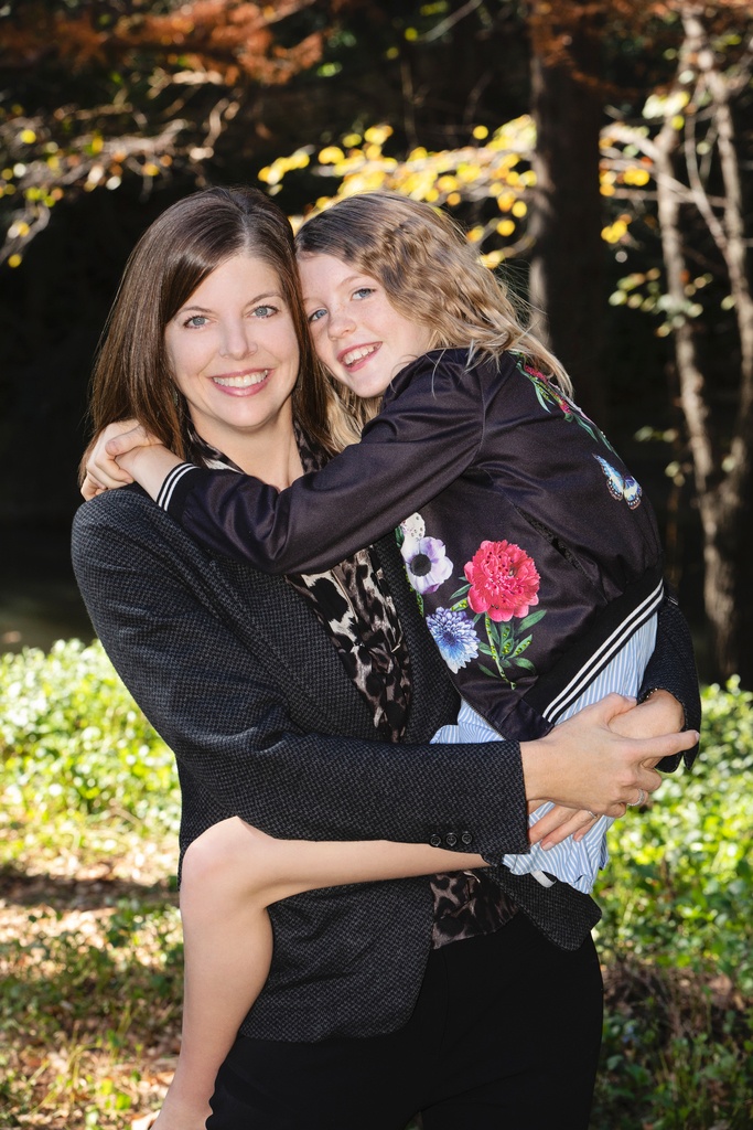 mom and daughter snuggle up for family photos outside