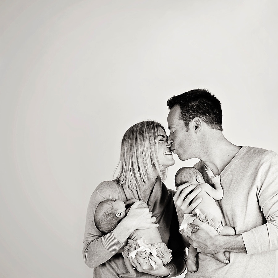 mom and dad being cute with newborn twins in private studio