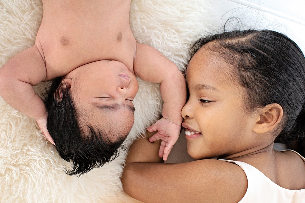 big sis and newborn sister grab adorable shots in private Dallas studio