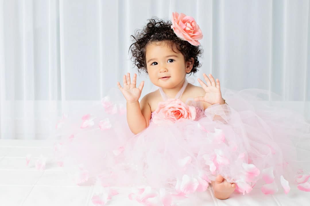 adorable little girl with detailed tutu and matching flower bow on her first birthday