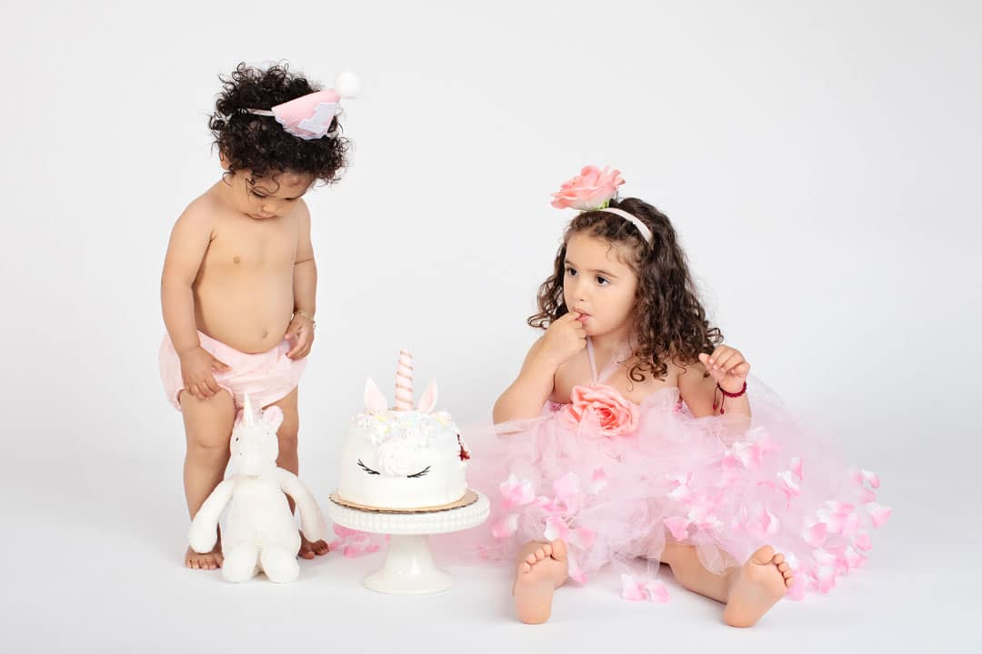 both sisters posing in dallas with unicorn cake