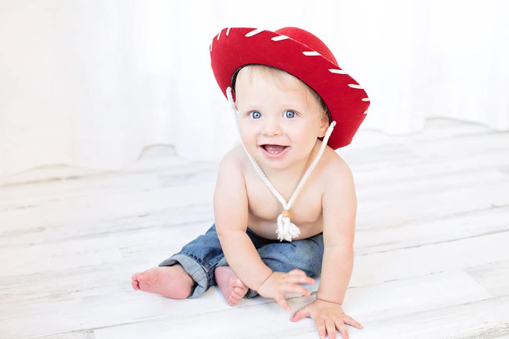 cute little boy with red cowboy hat posing in the studio