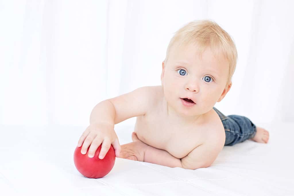 baby boy playing with a ball in the studio