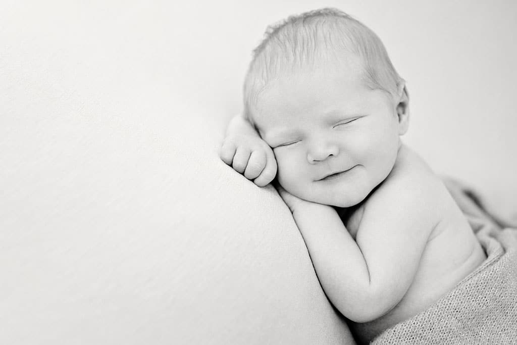 tender and sleepy smile on newborn baby