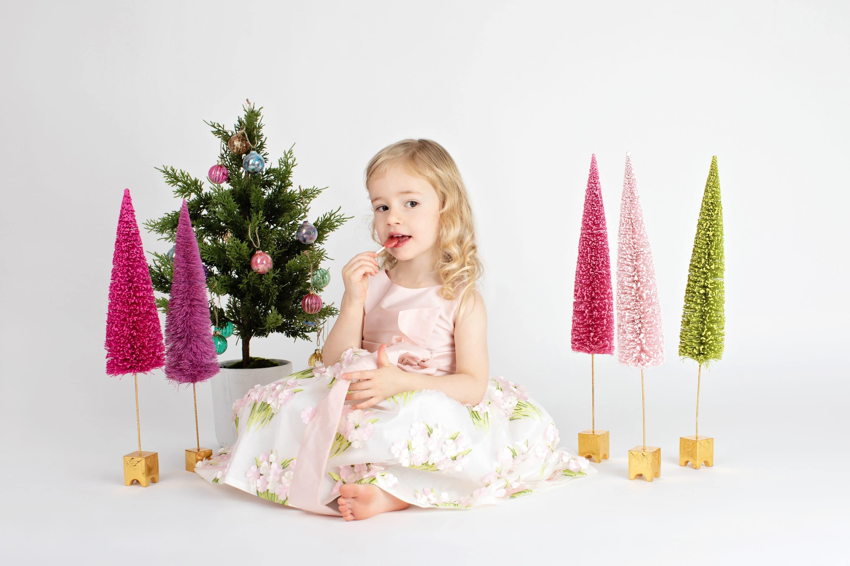 beautiful little girl posing with festive holiday trees