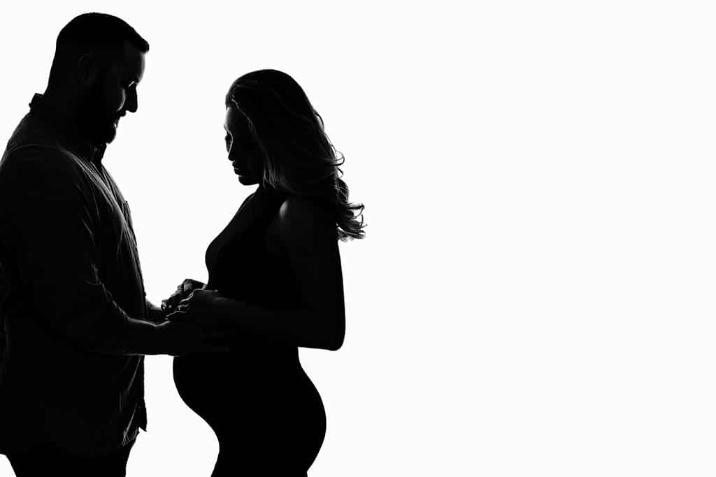 Expecting mother poses with husband caressing belly 