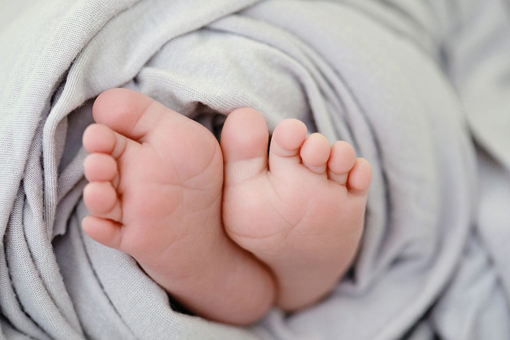 newborn baby toes cuddled up in soft blanket