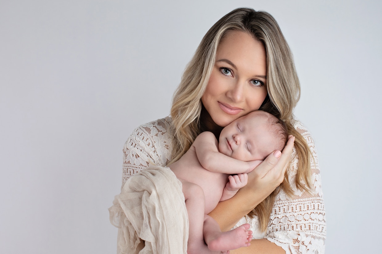New mom poses and admires her newborn baby