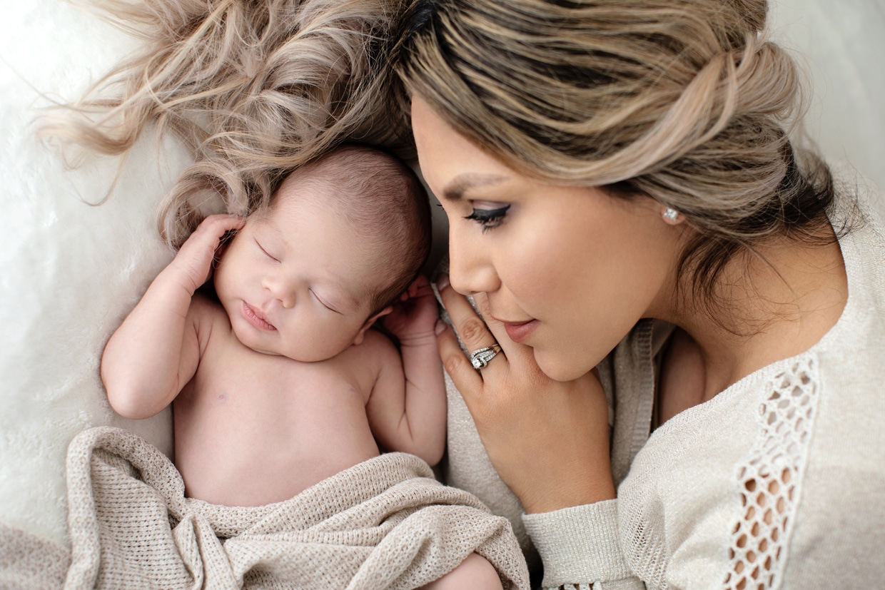 Mom poses with newborn baby boy in private studio