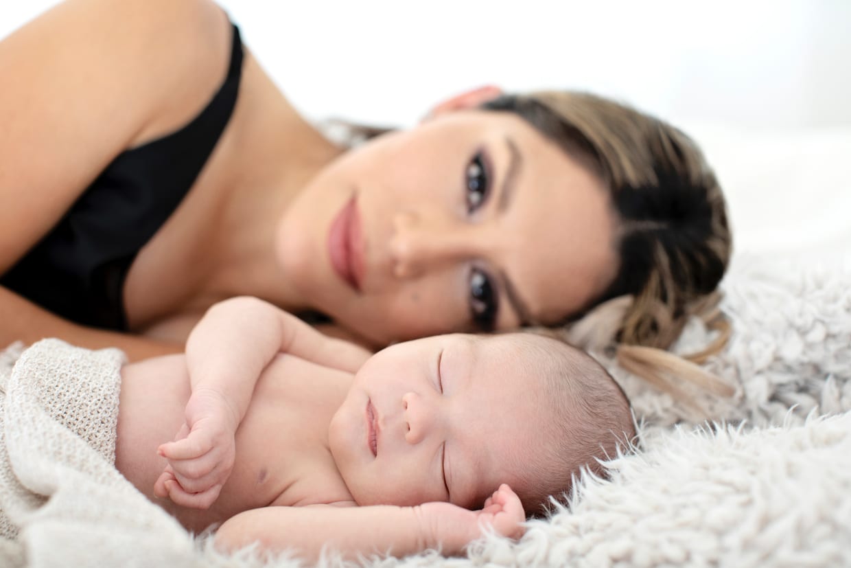 Mom poses with newborn baby boy in private studio