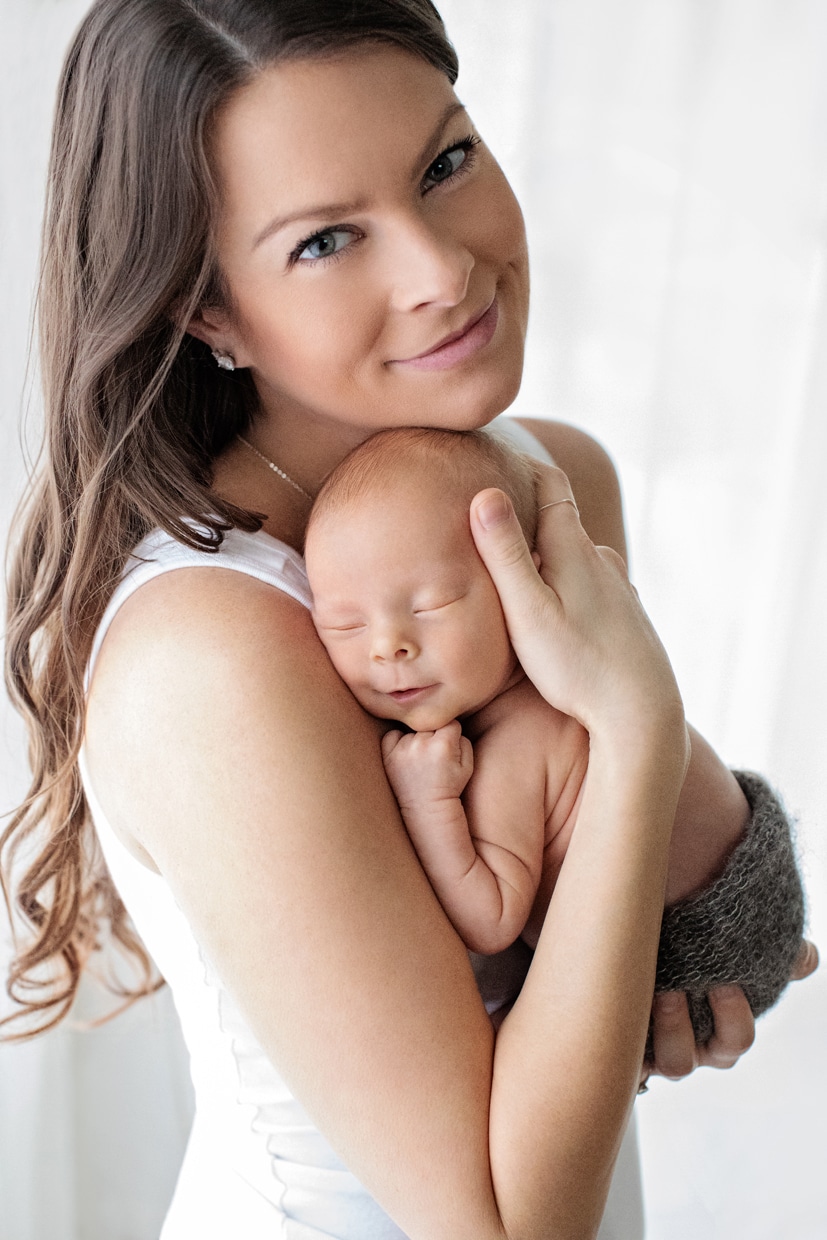 Mama snuggled up with her tiny newborn in dallas studio session