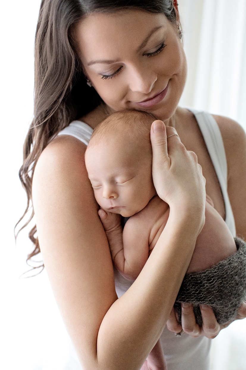 Mama snuggled up with her tiny newborn in dallas studio session