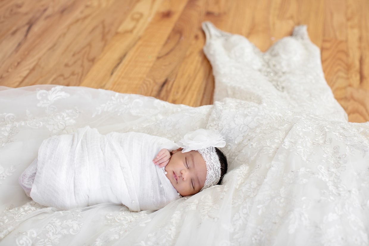 adorable baby girl snuggled up on moms wedding dress in private dallas studio session