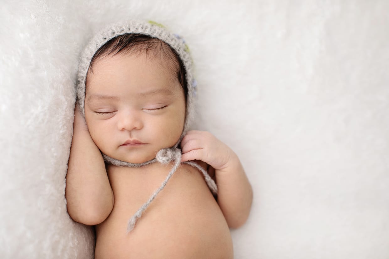 newborn girl cozied up in adorable knit hat in studio session