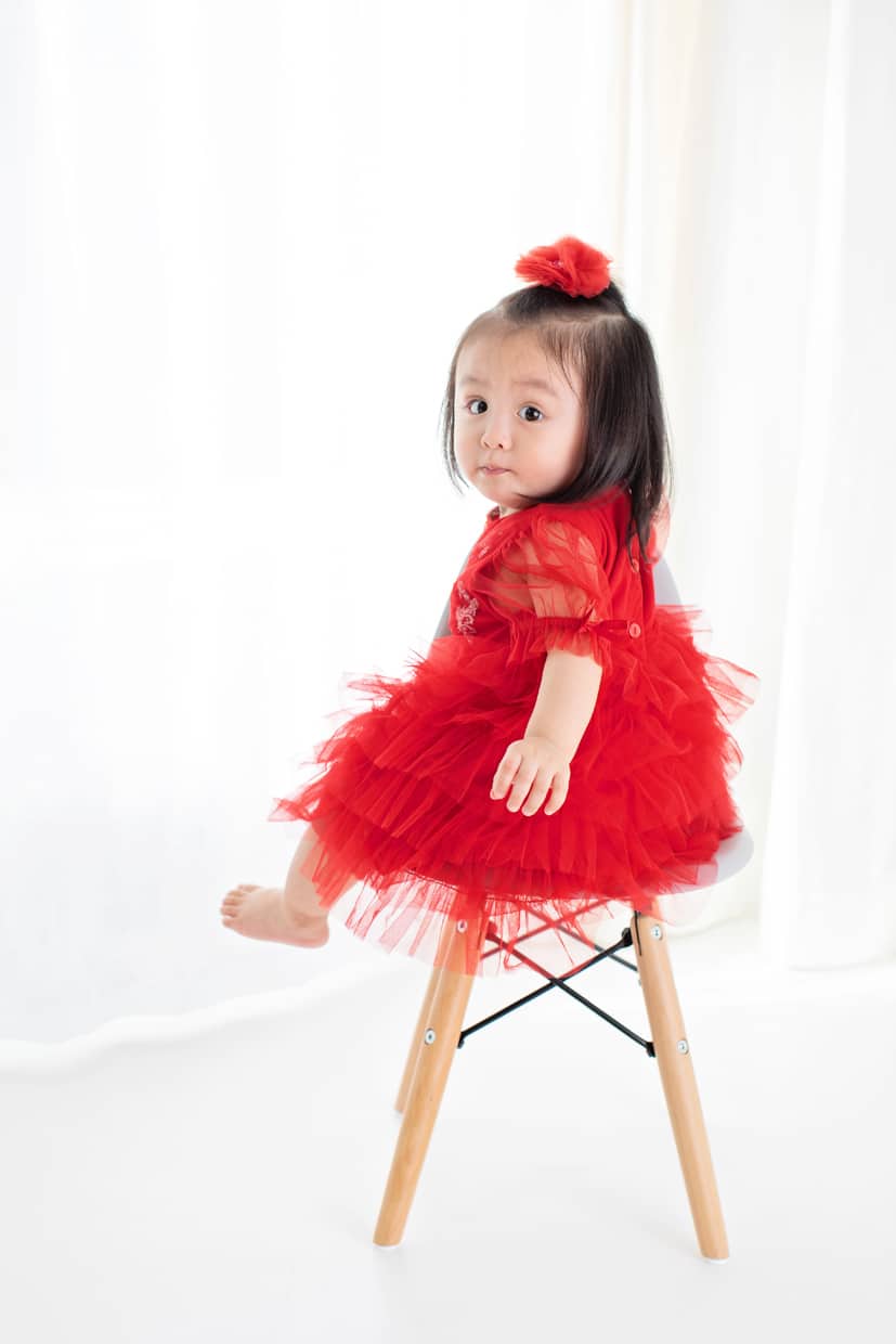 toddler girl in bright red dress posing for holidays session in private studio