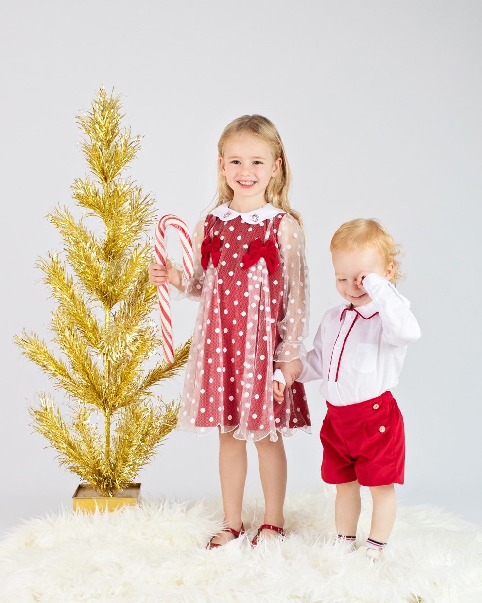 adorable kids posing in front of gold Christmas tree for the holidays