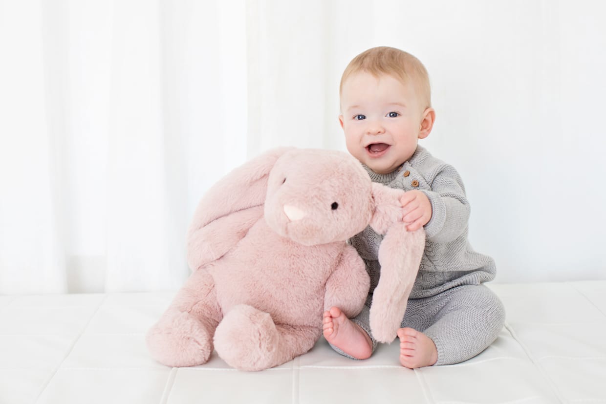 adorable baby posing with pink stuffed bunny in private studio