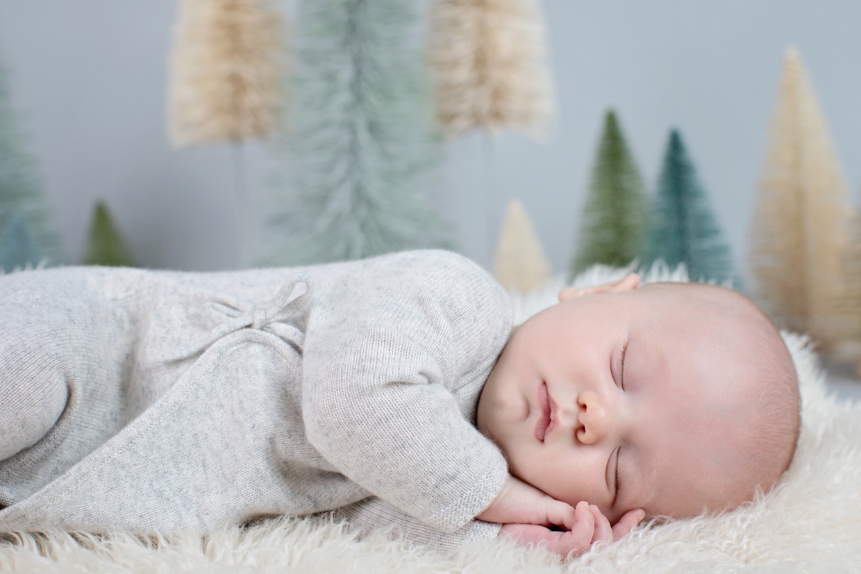 cute newborn sleeping in front of Christmas trees in dallas studio