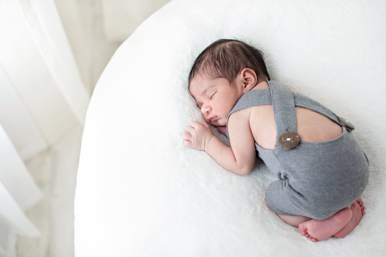 Adorable baby girl snuggled up on bean bag in overalls in private dallas studio
