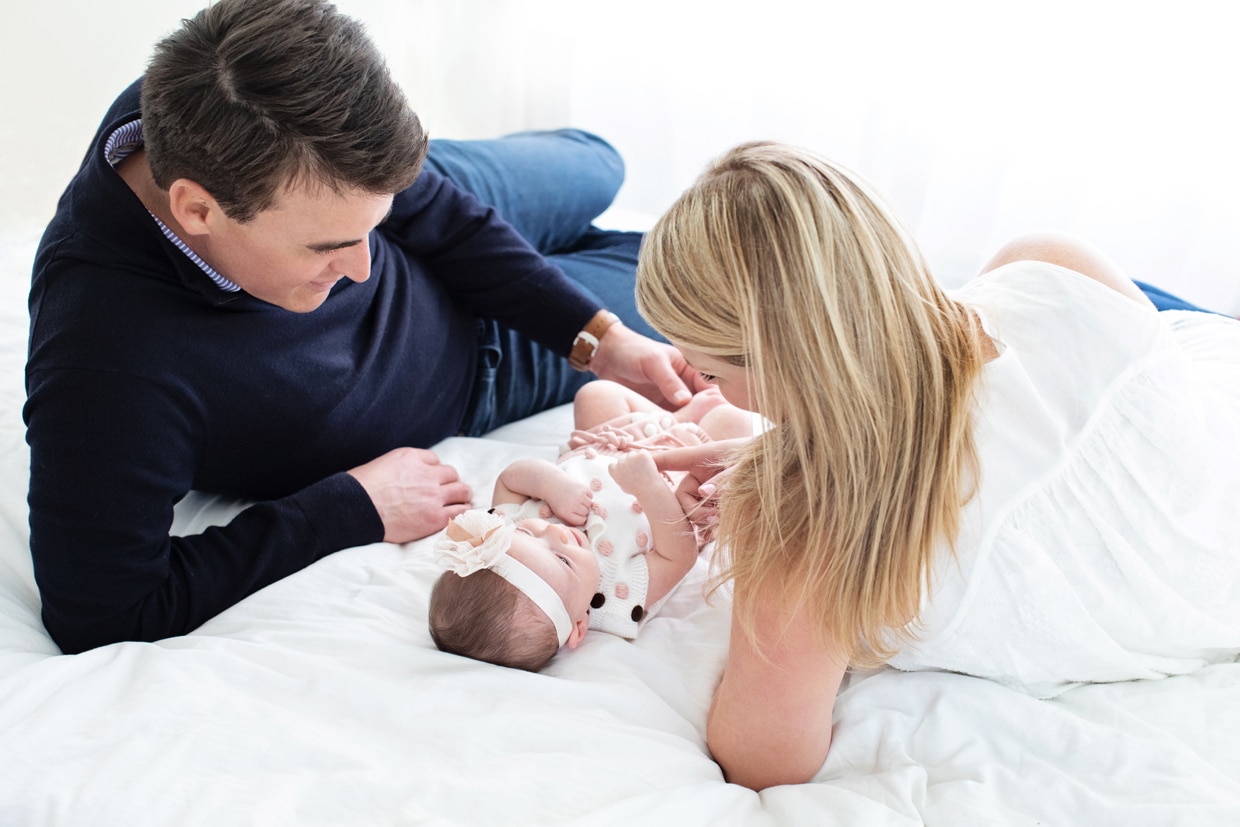 New mom and dad looking at their two-month old baby in private dallas studio.