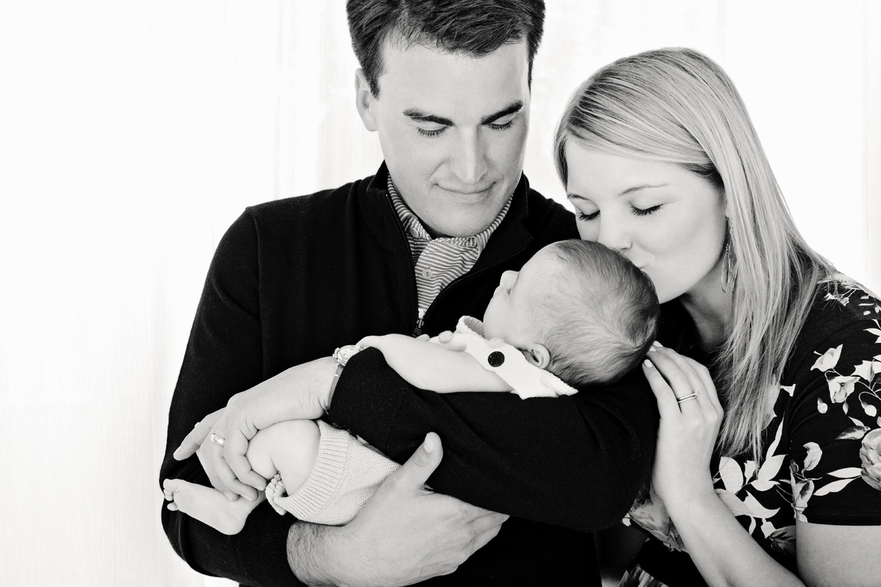 mom and dad cuddle with newborn baby girl in private studio session