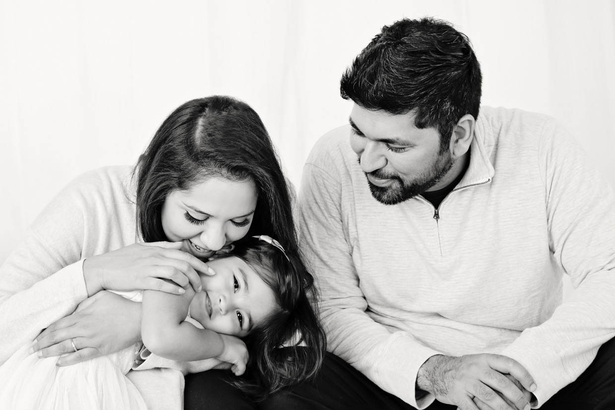 Adorable and bashful toddler cozy's up to mom and dad in private dallas studio