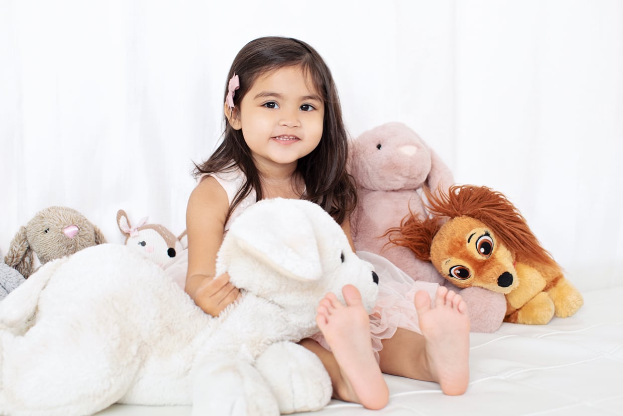 Little girl snuggles with an entourage of stuffed animals