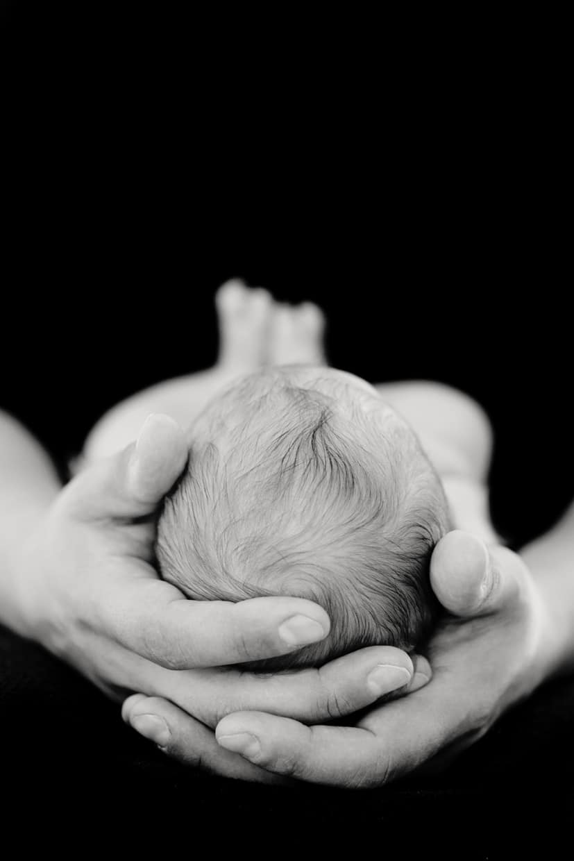 close up of the top of a newborn's head being held in dad's hands in private dallas studio