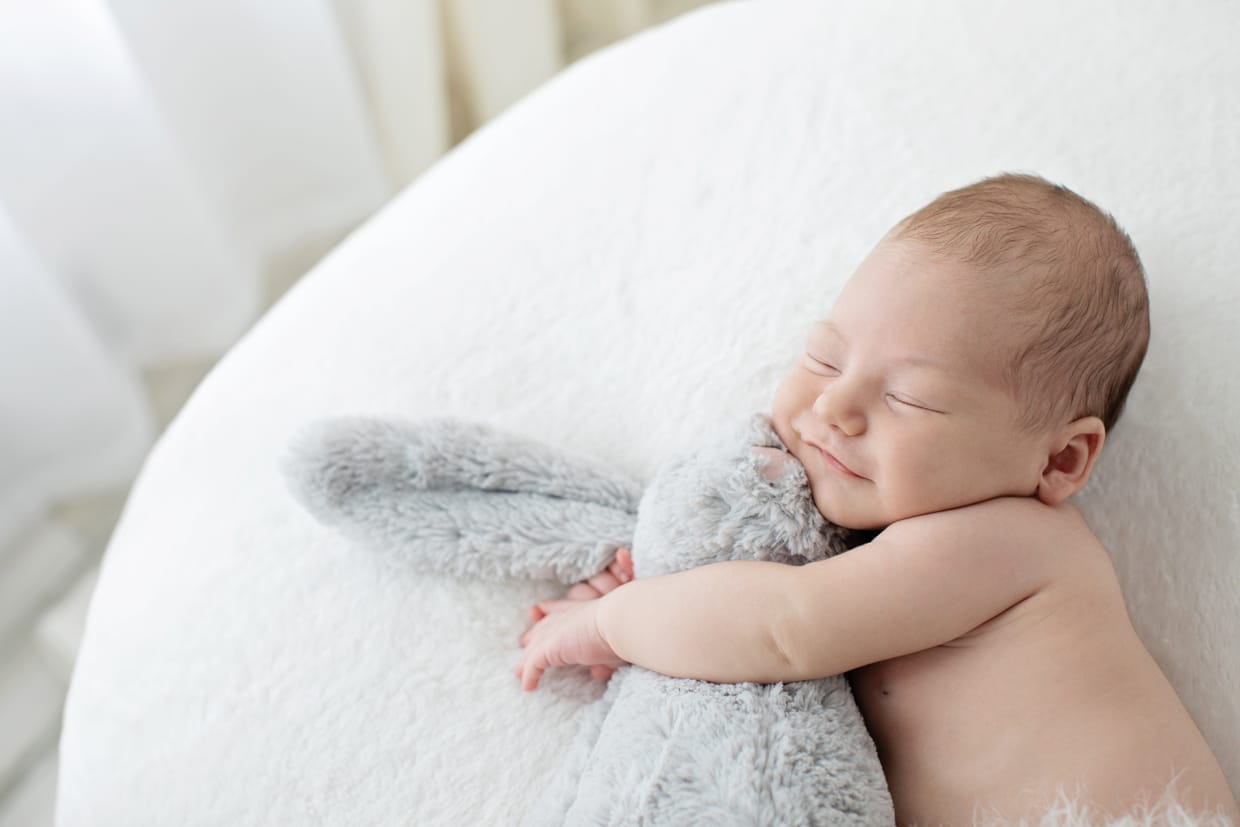 newborn baby cuddles with stuffed bunny in studio session