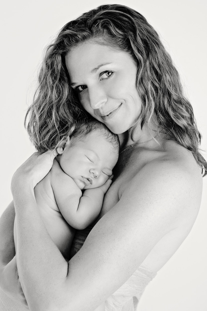New mom enjoying baby bliss while holding newborn baby girl in private dallas studio