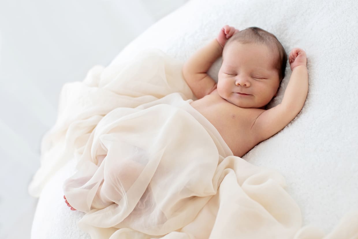 black and white photo of sleeping newborn baby girl stretching