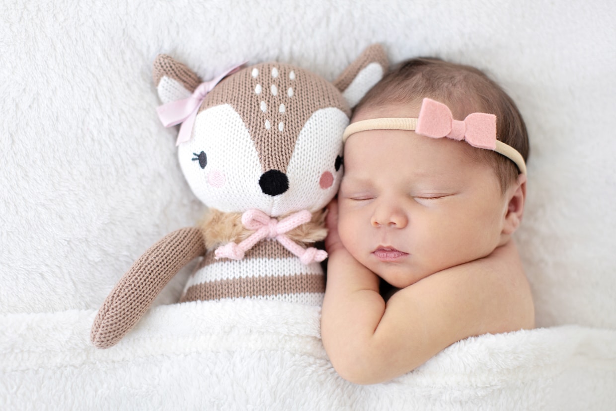 adorable newborn cozied up to stuffed animal 