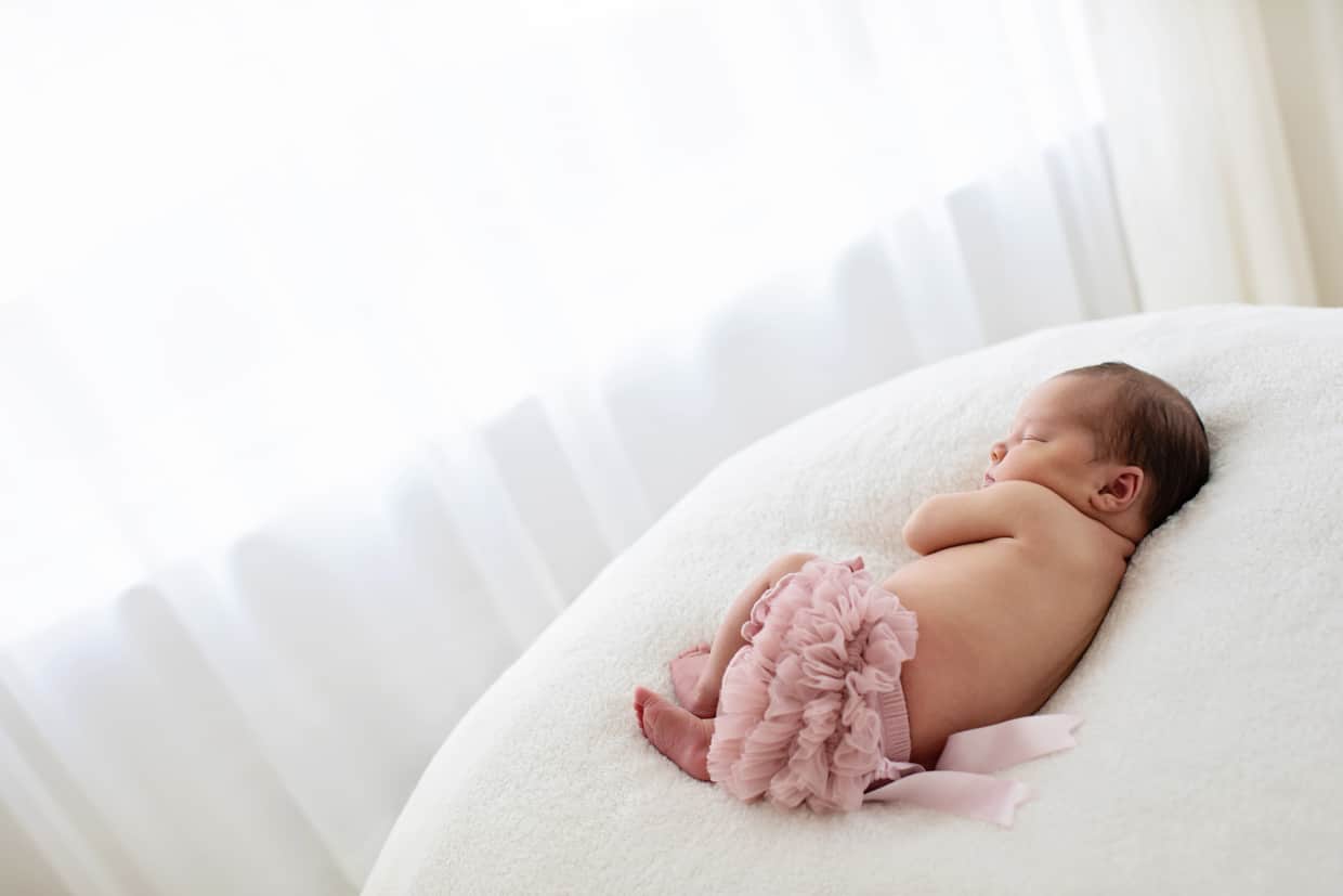 adorable newborn in ruffled diaper cover on white bean bag