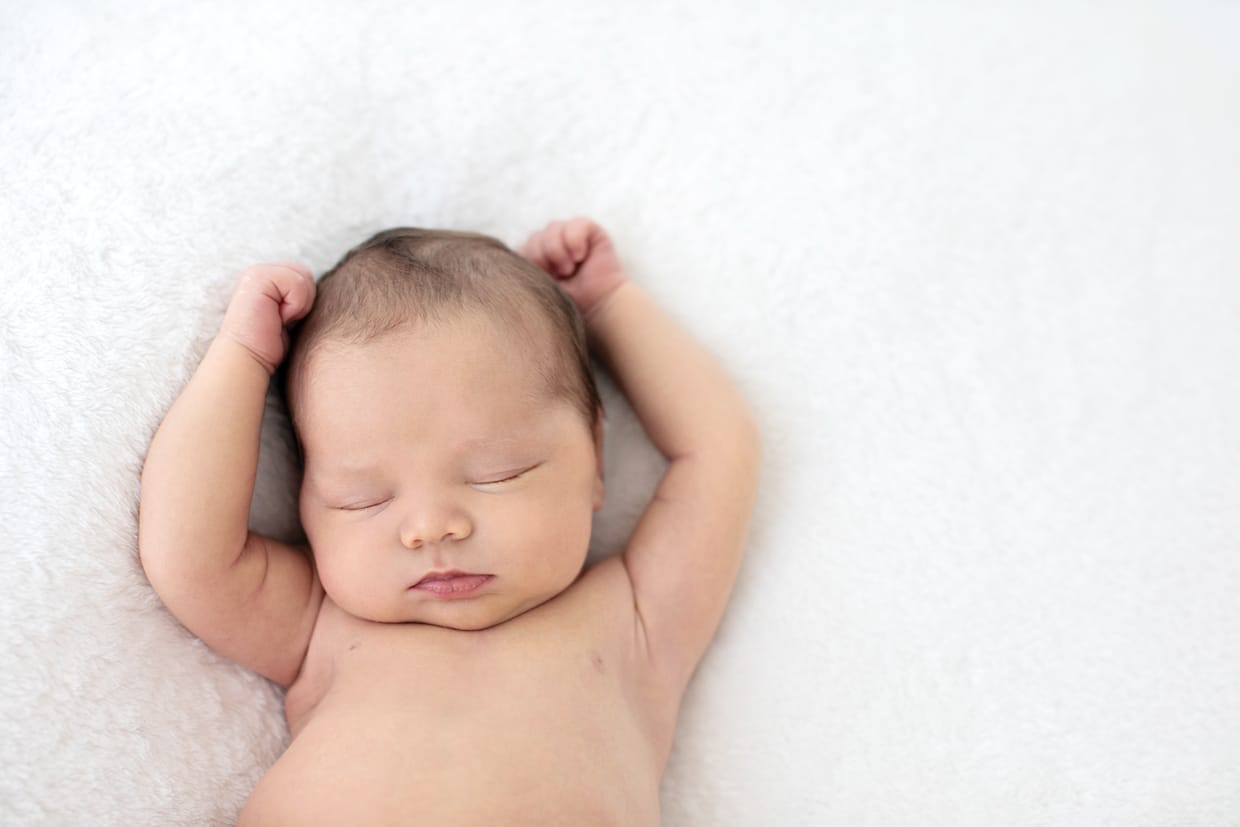 black and white photo of sleeping newborn baby girl stretching 