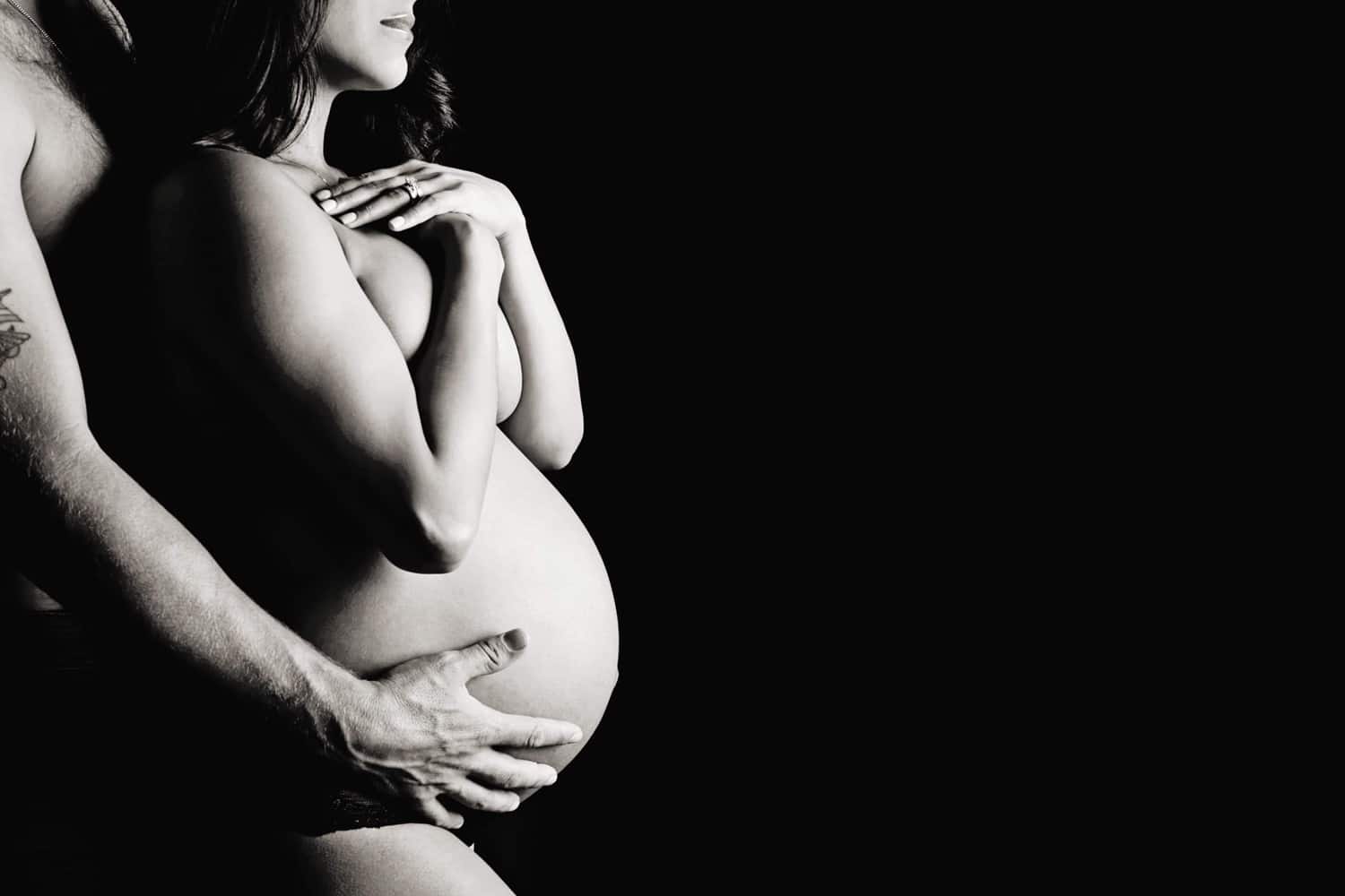 A man and a woman in a black and white maternity photo.