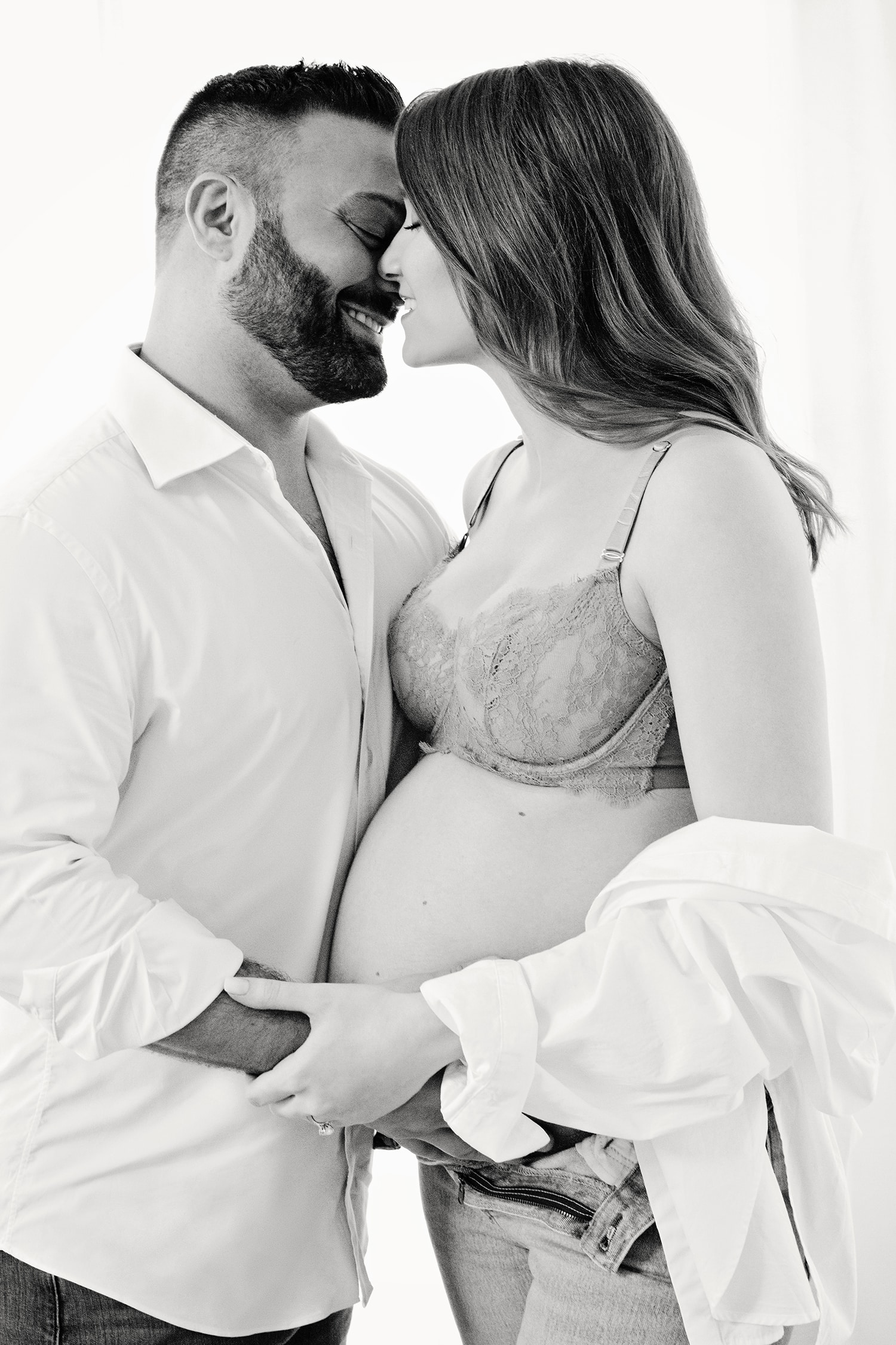 A husband and wife lean into each other for a maternity portrait.