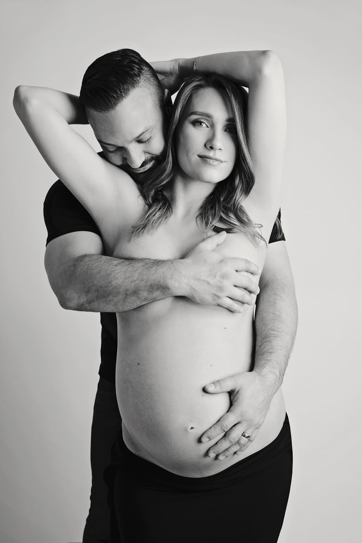 A husband embraces his pregnant wife for a maternity portrait.