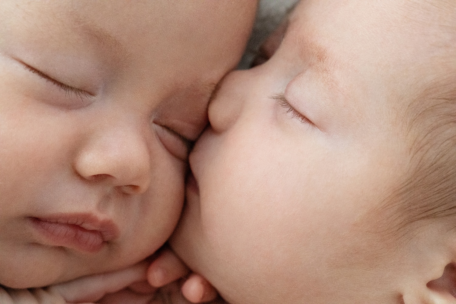 Two newborn babies kiss one another.