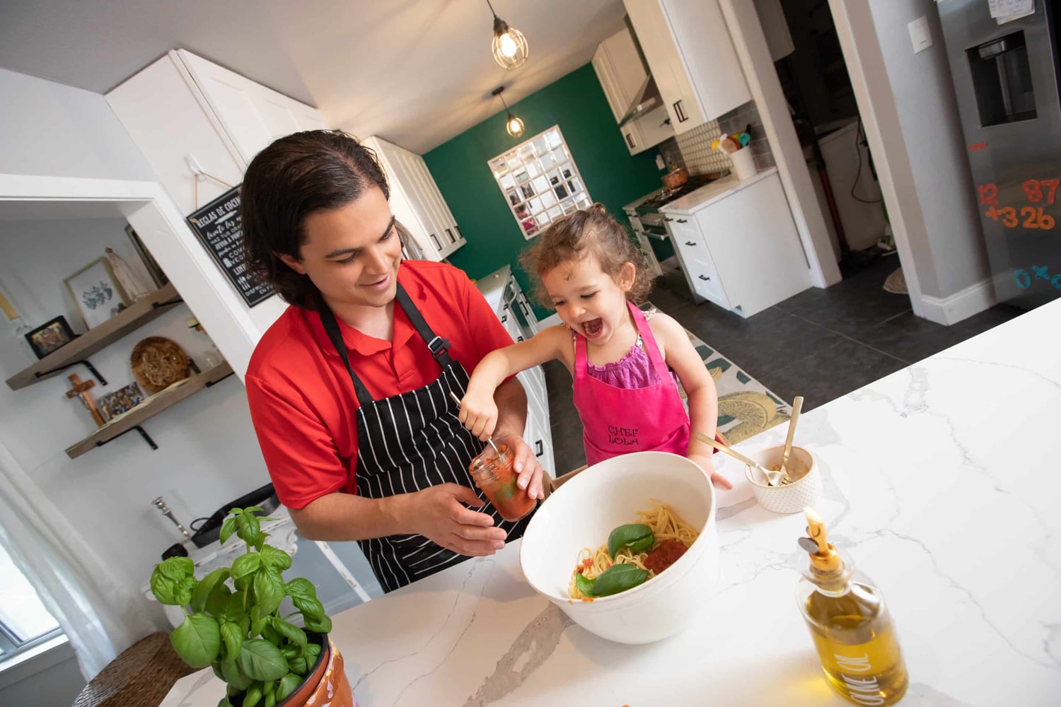 A little girl cooks with her dad at home.