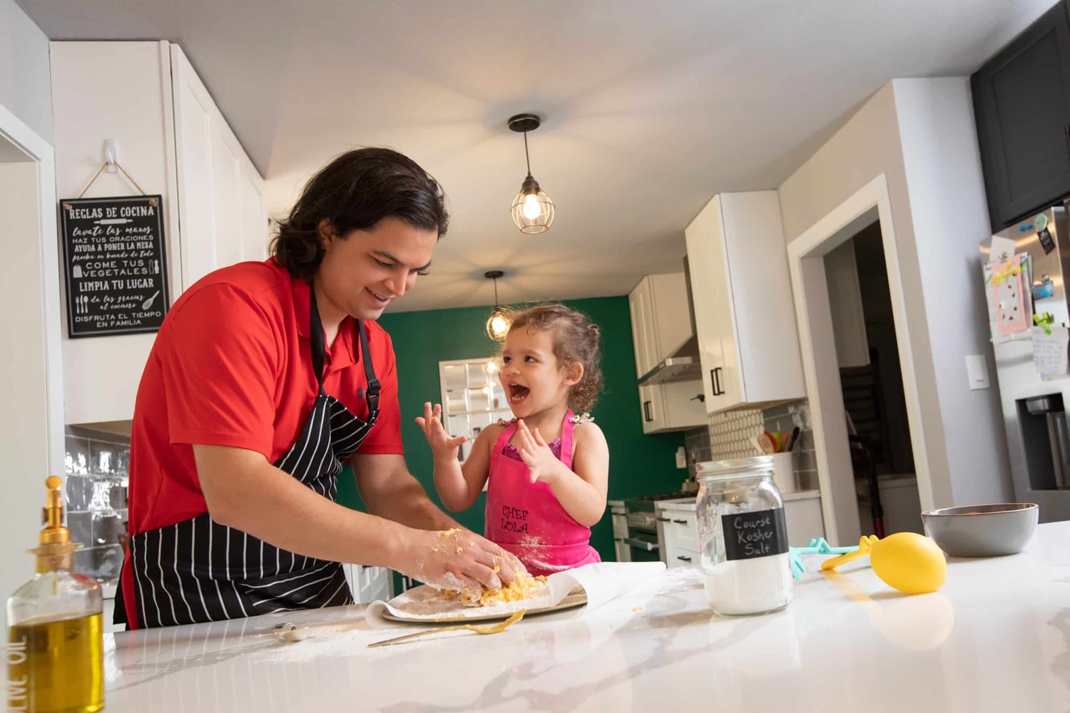 A little girl cooks with her dad at home.