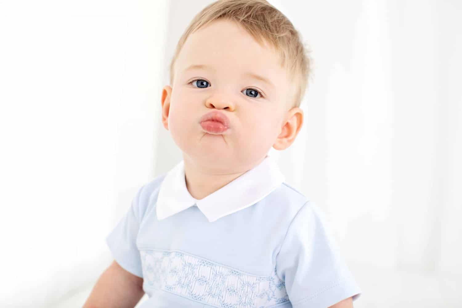 A boy blows a kiss to the camera.