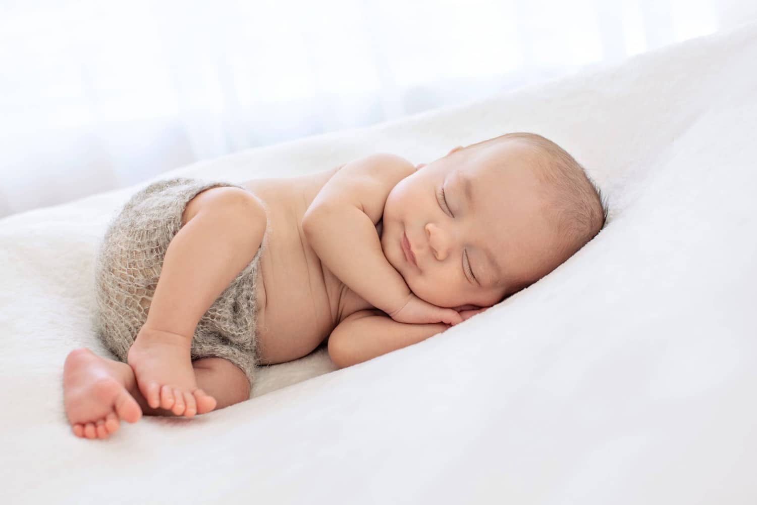 A baby snuggles on a white pillow.