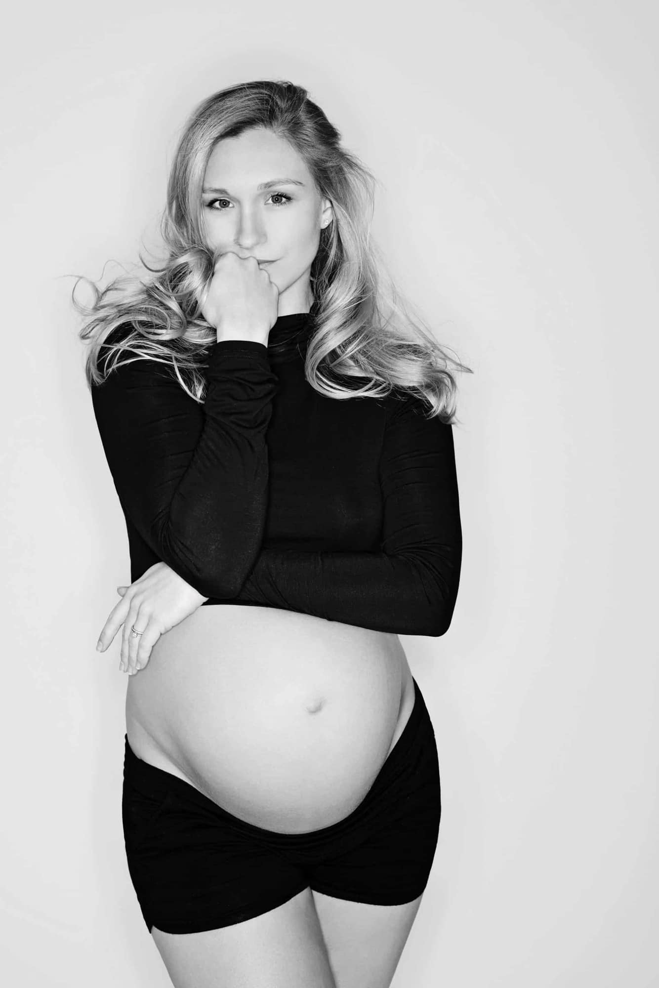 A black & white maternity photo of a woman in black top and bottoms.