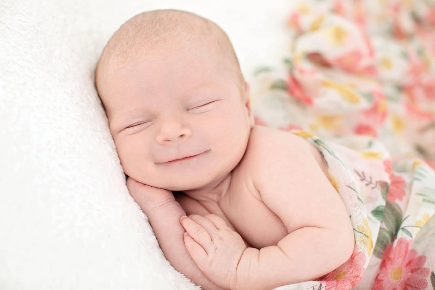 A newborn baby smiles in a portrait.